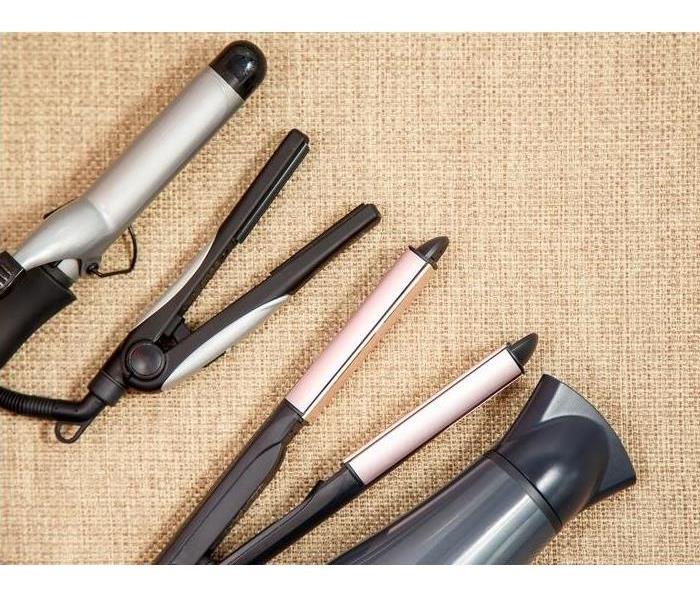 various hair appliances; metal curling iron, two hair straightners, and black blow dryer