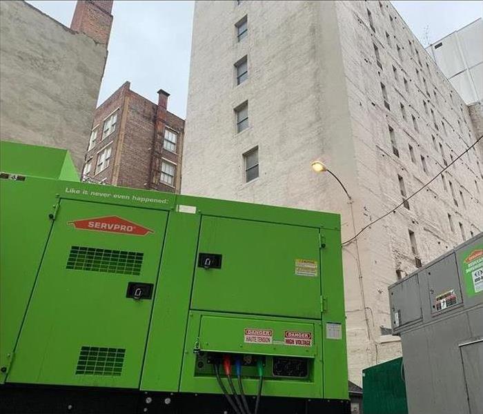 A tall big green machine doing its job o0f drying a commercial building 