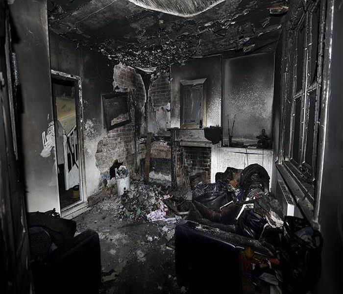A room is severely burnt and black, destroyed by a fire